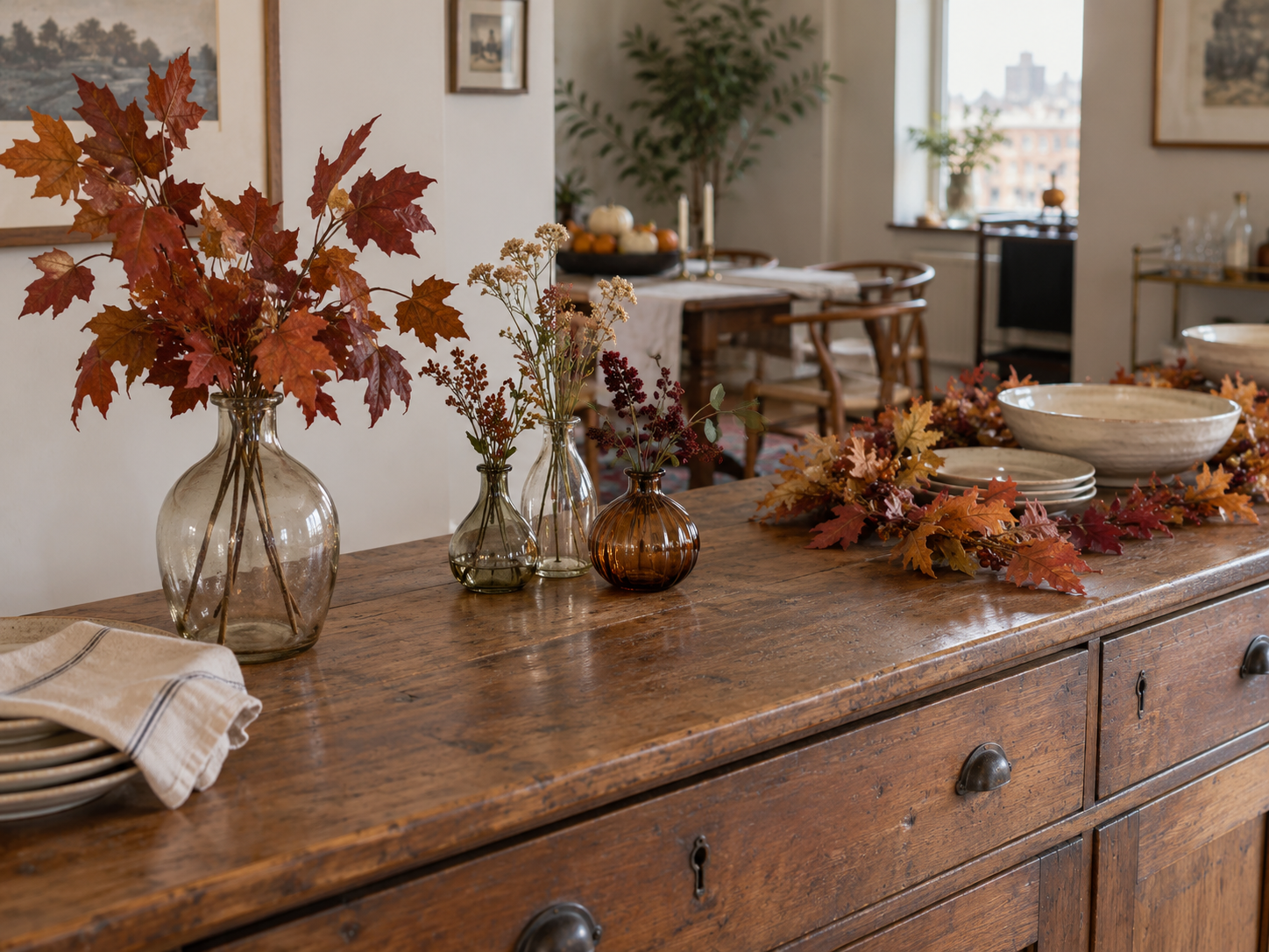 Three low Thanksgiving centerpiece ideas with glass vases, faux fall leaves and a short leaf garland